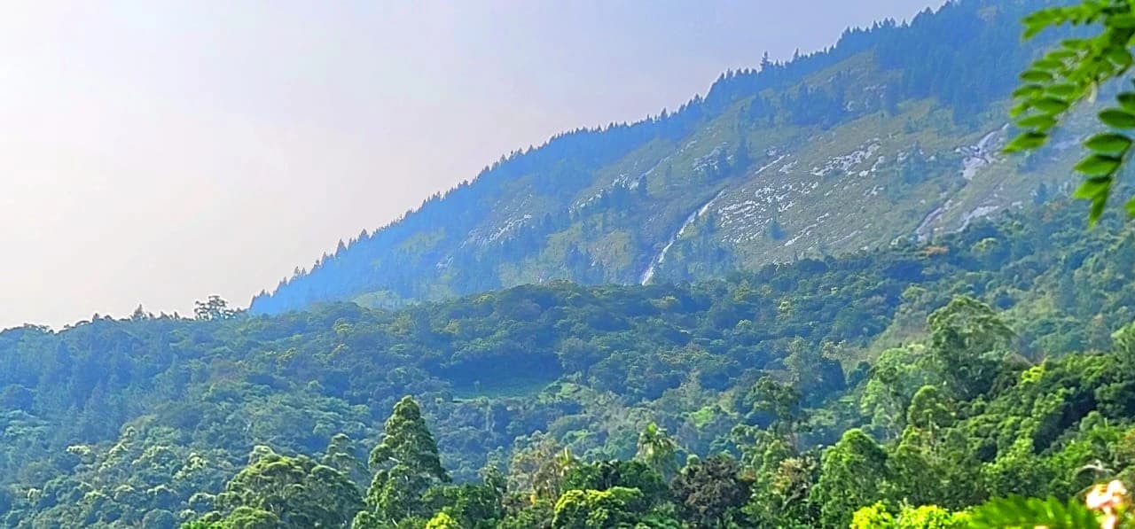 Scenic view of lush green mountains and a distant waterfall in the Belihuloya hillside.